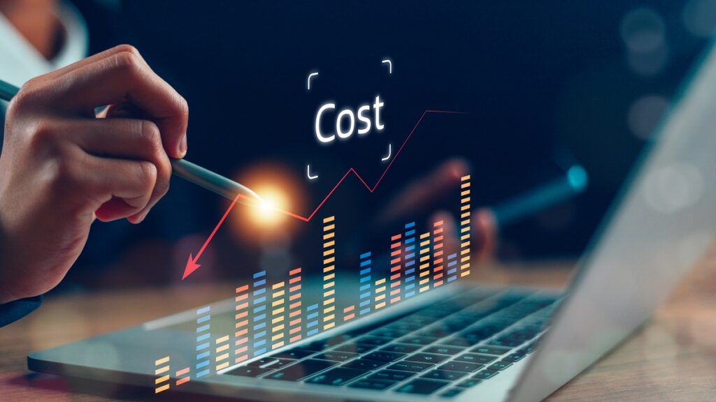 A hand holding a pen hovers over a laptop displaying a vibrant cost analysis graph with upward trends and colorful bars.